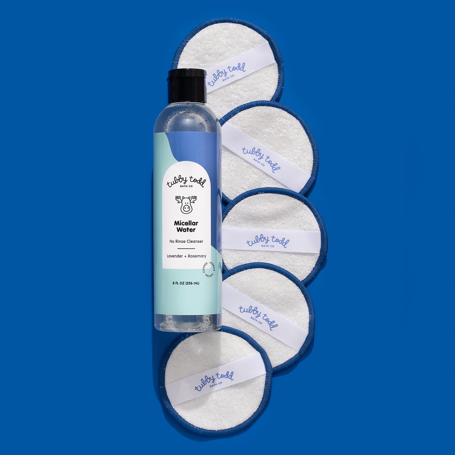 Lavender Rosemary Micellar Water bottle lying with the cotton pads on the blue color background.
